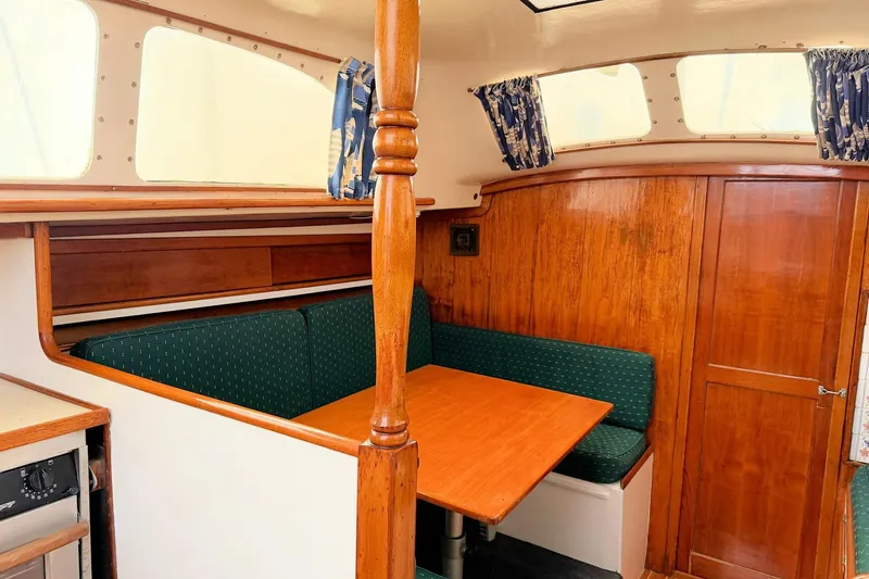 Slide: The Image of 1967 Columbia Constellation yacht interior with wooden dining area and green cushioned seating. - 88