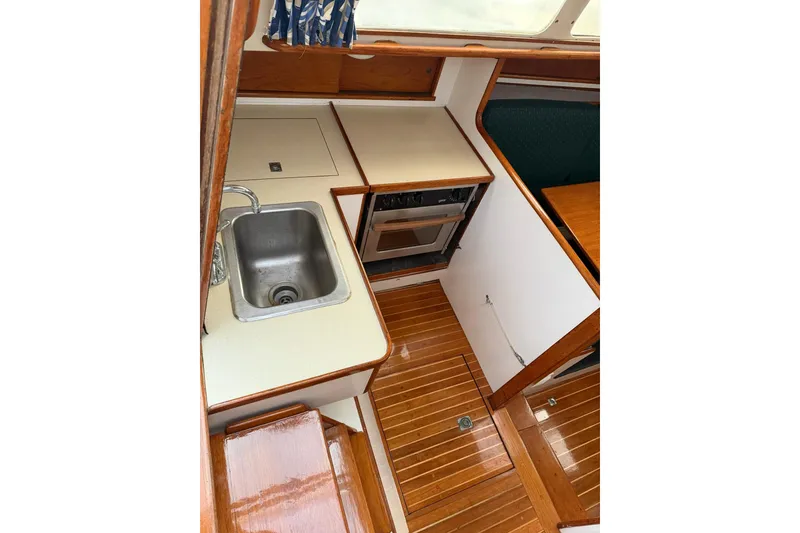 Slide: The Image of 1967 Columbia Constellation yacht interior with compact kitchen, sink, and wooden flooring. - 92