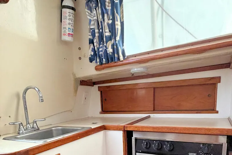 Slide: The Image of 1967 Columbia Constellation boat interior with sink, stove, and nautical-themed curtains. - 97