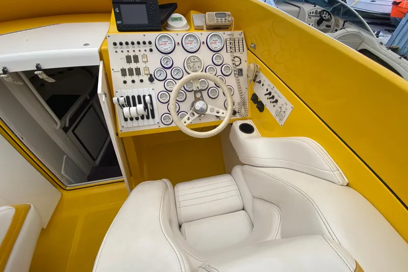 Slide: The Image of Cockpit of a 1999 Fountain 47 Lightning boat with yellow dashboard and white seating. - 23