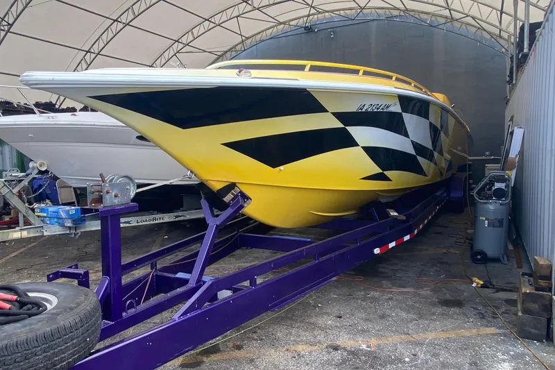 Slide: The Image of 1999 Fountain 47 Lightning boat with bold yellow and black design on trailer. - 3