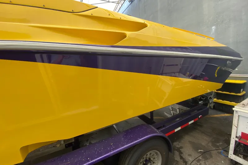 Slide: The Image of Yellow and purple 1999 Fountain 47 Lightning boat on trailer in a garage. - 36