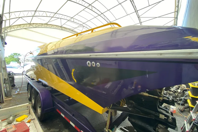Slide: The Image of 1999 Fountain 47 Lightning boat in a covered storage, vibrant purple and yellow design. - 37