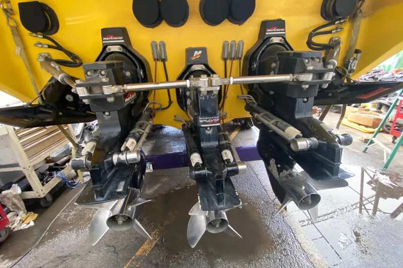 Slide: The Image of 1999 Fountain 47 Lightning boat with triple MerCruiser Bravo engines in a workshop setting. - 46