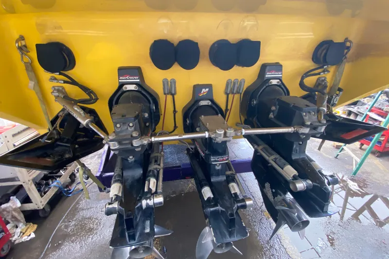 Slide: The Image of 1999 Fountain 47 Lightning boat with triple MerCruiser outdrives in a workshop setting. - 47