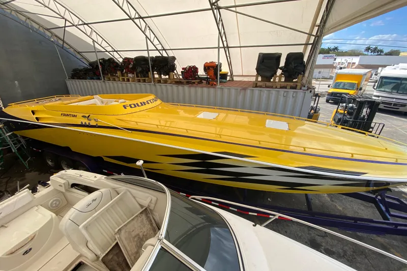 Slide: The Image of Yellow 1999 Fountain 47 Lightning speedboat under a canopy, parked on a trailer. - 6