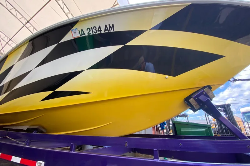 Slide: The Image of 1999 Fountain 47 Lightning boat with bold yellow and black design on trailer. - 7