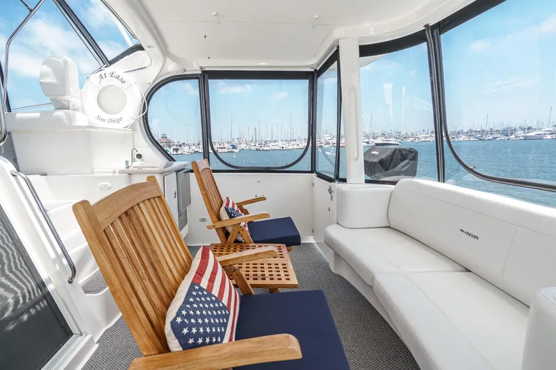 Slide: The Image of 2004 Silverton 39 Motor Yacht interior with wooden chairs, American flag pillows, and marina view. - 11