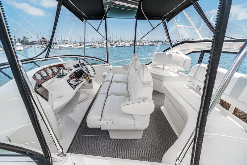 Slide: The Image of 2004 Silverton 39 Motor Yacht interior with white seating and helm, overlooking marina. - 16