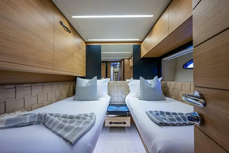 Slide: The Image of Luxurious twin cabin interior on 2014 Pershing 92 yacht, featuring modern wood finishes and elegant bedding. - 20