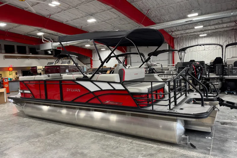 Slide: The Image of 2026 Sylvan X-5 pontoon boat in showroom, featuring red and black design with canopy. - 3