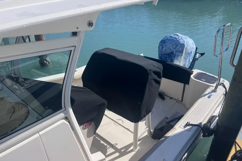 Slide: The Image of 2015 Scout 255 LXF boat interior with covered seats and engine by the water. - 16