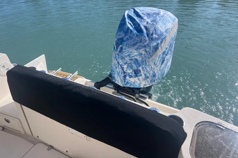 Slide: The Image of 2015 Scout 255 LXF boat with covered outboard motor on calm water. - 21