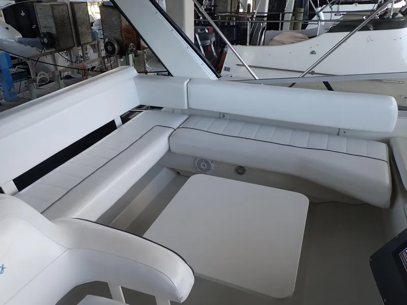 Slide: The Image of 1996 Carver 370 Voyager interior with white seating and table in a marina setting. - 5