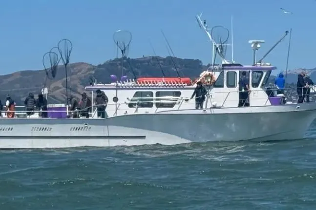 The Image of 1978 Uniflite 50 boat on water with people, fishing nets, and scenic background. - 1