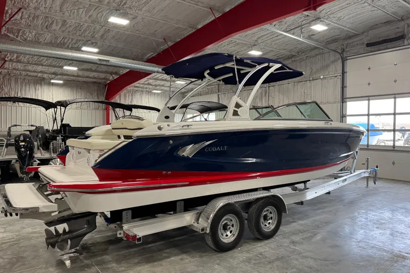 Slide: The Image of 2017 Cobalt A28 boat in showroom, blue and red design, on a trailer. - 3