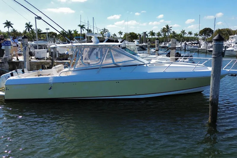 The Image of 2001 Intrepid 377 Walkaround boat docked in a marina with palm trees. - 1