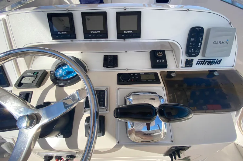 Slide: The Image of 2001 Intrepid 377 Walkaround boat dashboard with Suzuki controls and Garmin navigation. - 27