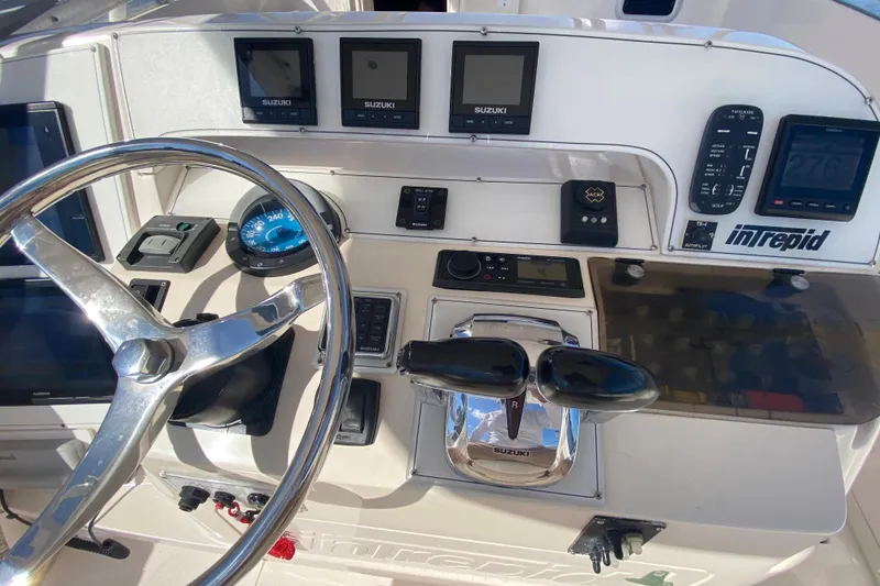Slide: The Image of 2001 Intrepid 377 Walkaround boat dashboard with steering wheel and control panels. - 28
