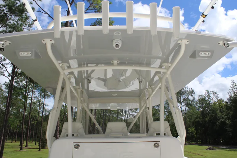 Slide: The Image of 2022 SeaVee 370Z boat with T-top, rod holders, and lush forest backdrop. - 24