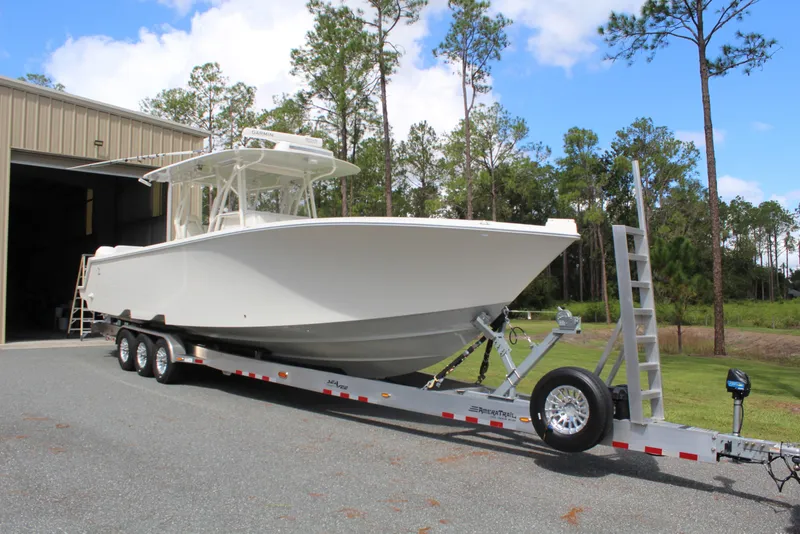 Slide: The Image of 2022 SeaVee 370Z boat on trailer outside a garage, surrounded by trees. - 3