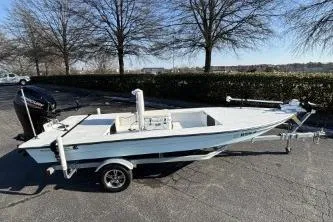 Slide: The Image of 2021 Skimmer Skiff boat on trailer, parked outdoors, surrounded by trees. - 4