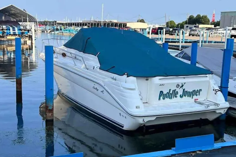 Slide: The Image of 1996 Sea Ray 270 Sundancer boat named "Puddle Jumper" docked with blue cover. - 3