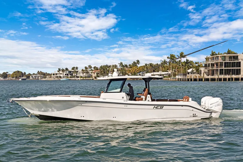 The Image of 2023 HCB Speciale boat cruising on a sunny day near waterfront homes. - 0
