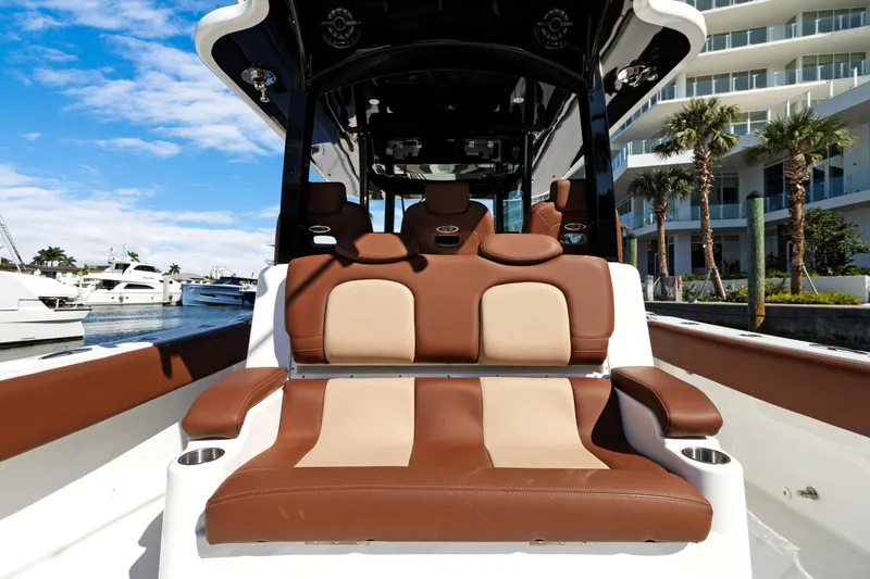 Slide: The Image of 2023 HCB Speciale boat interior with luxurious brown and beige seating, docked near palm trees. - 14