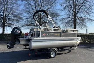 Slide: The Image of 2025 Sun Tracker Party Barge 16 DLX pontoon boat on trailer, parked outdoors. - 3