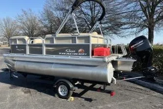 Slide: The Image of 2025 Sun Tracker Party Barge 16 DLX pontoon boat on trailer, parked outdoors. - 4