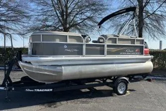 Slide: The Image of 2025 Sun Tracker Party Barge 16 DLX pontoon boat on trailer, parked outdoors. - 5