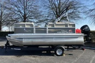 Slide: The Image of 2025 Sun Tracker Party Barge 16 DLX pontoon boat on trailer, parked outdoors. - 6
