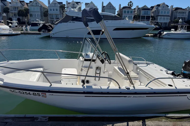 Slide: The Image of 2006 Boston Whaler 180 Dauntless boat docked in marina with waterfront homes. - 2