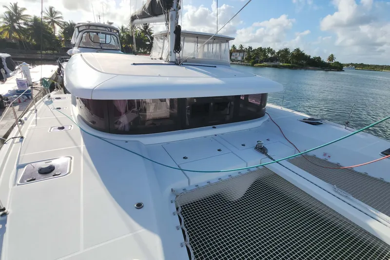Slide: The Image of 2020 Lagoon 42 catamaran docked by tropical shoreline, featuring spacious deck and modern design. - 1