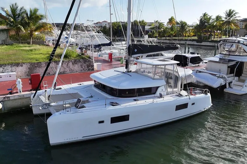 Slide: The Image of 2020 Lagoon 42 catamaran docked in a marina with lush surroundings. - 19
