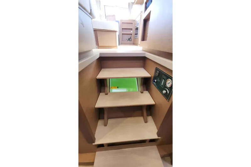 Slide: The Image of Interior stairs of 2020 Lagoon 42 catamaran, featuring wooden steps and control panel. - 51