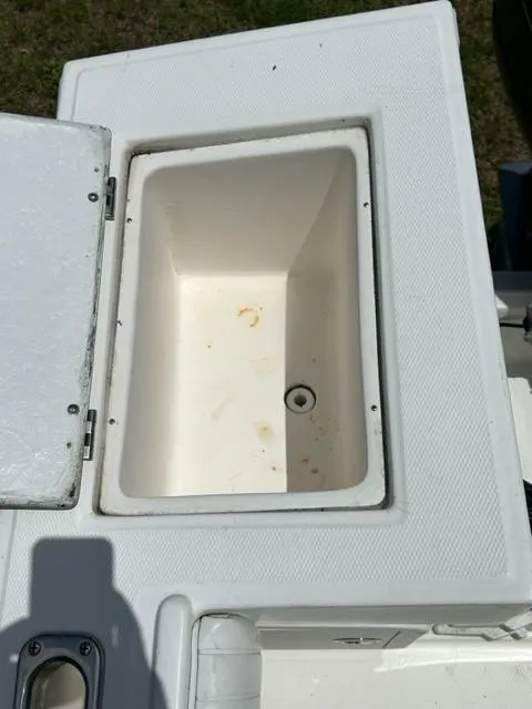 Slide: The Image of 2000 Regulator 23' Center Console boat storage compartment, open lid, white interior. - 19