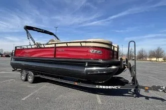 The Image of 2025 Regency 250 DL3 pontoon boat on trailer under clear blue sky. - 0