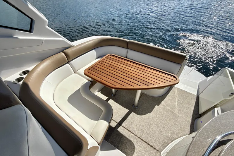 Slide: The Image of 2016 Four Winns V335 boat with elegant seating and wooden table on deck. - 12