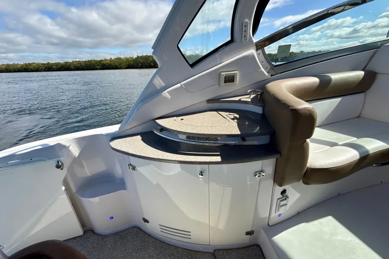 Slide: The Image of 2016 Four Winns V335 boat interior with seating and countertop, overlooking serene water. - 14