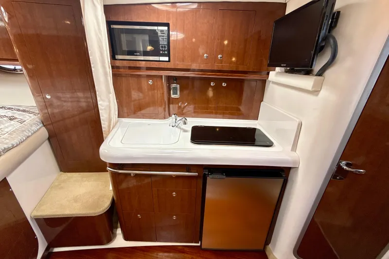 Slide: The Image of 2016 Four Winns V335 yacht interior with kitchenette, featuring microwave, sink, and mini-fridge. - 21