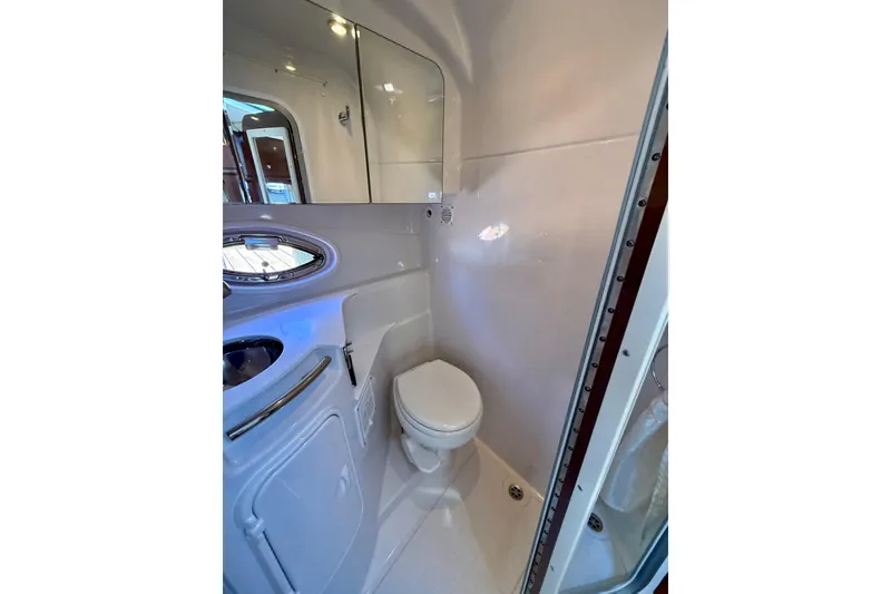 Slide: The Image of 2016 Four Winns V335 boat bathroom with toilet, sink, and mirror. - 30