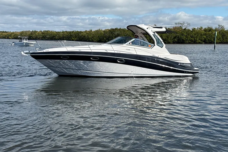 Slide: The Image of 2016 Four Winns V335 boat on calm water, showcasing sleek design and modern features. - 32