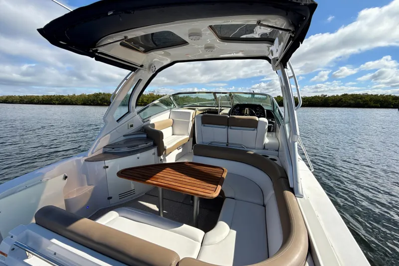 Slide: The Image of 2016 Four Winns V335 boat interior with seating and table on a sunny day. - 5