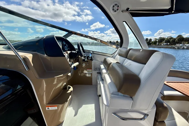 Slide: The Image of 2016 Four Winns V335 boat interior with leather seating and steering console, under a sunny sky. - 6