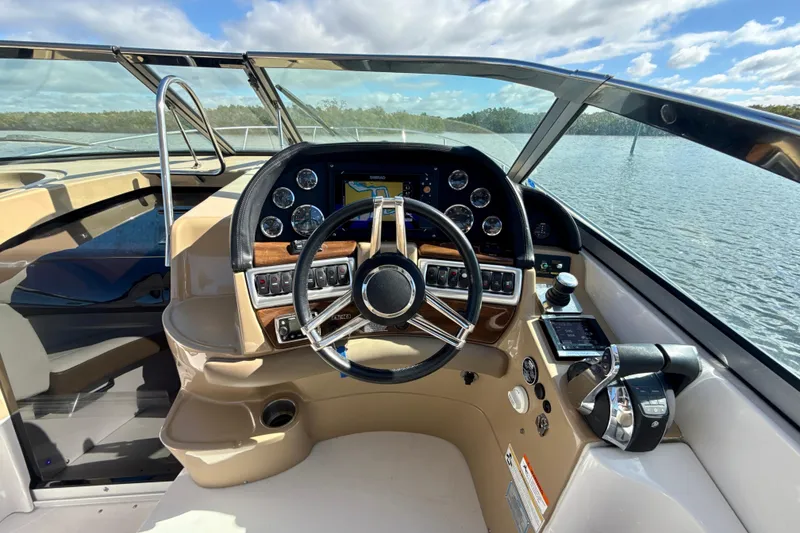 Slide: The Image of 2016 Four Winns V335 boat cockpit with steering wheel and control panel on a sunny day. - 9