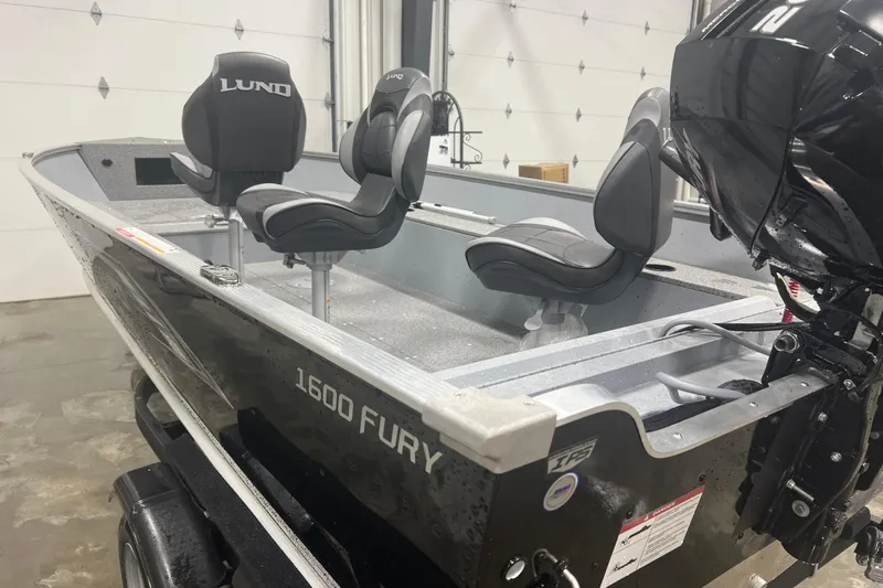 The Image of 2026 Lund 1600 Fury Tiller boat with black exterior and comfortable seating in a garage. - 1