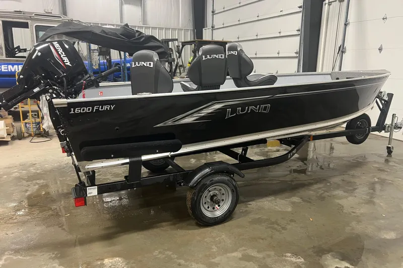 Slide: The Image of 2026 Lund 1600 Fury Tiller boat on trailer in garage setting. - 4