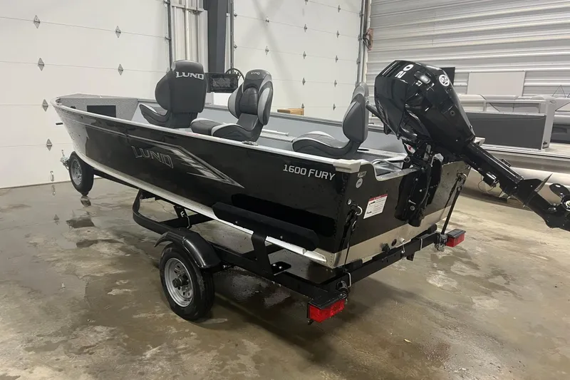 Slide: The Image of 2026 Lund 1600 Fury Tiller boat in garage, featuring sleek design and powerful outboard motor. - 7